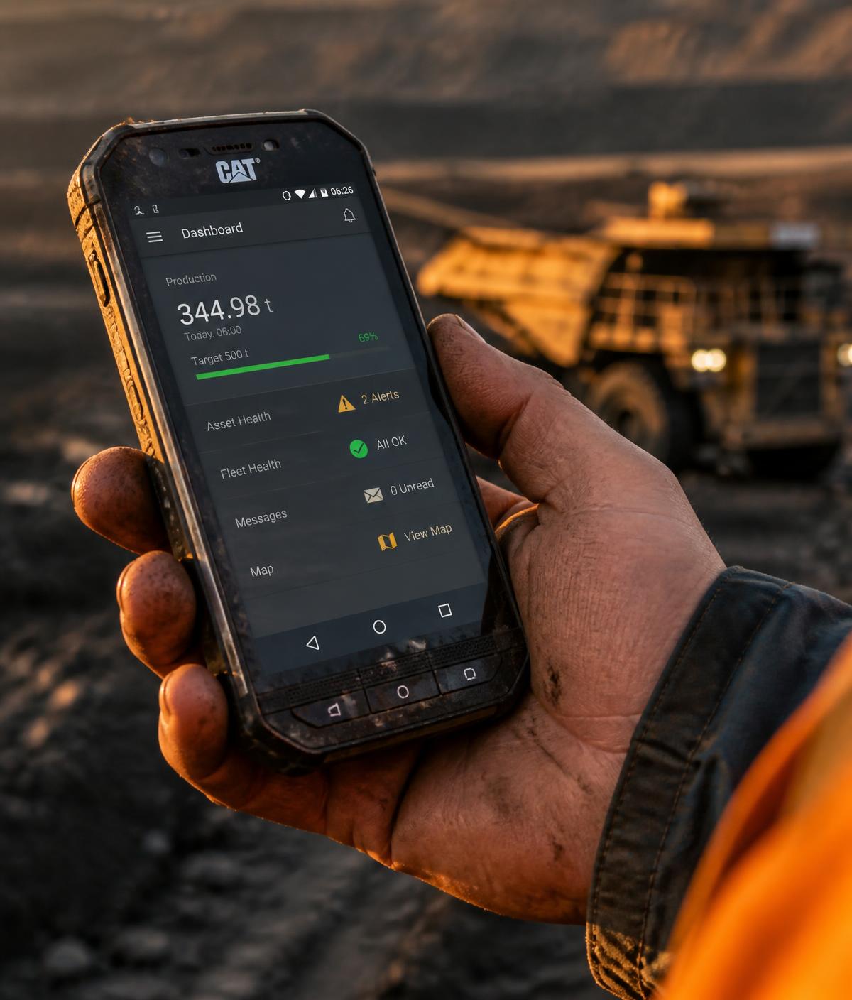 Worker checking mining operations data on a mobile phone at a site